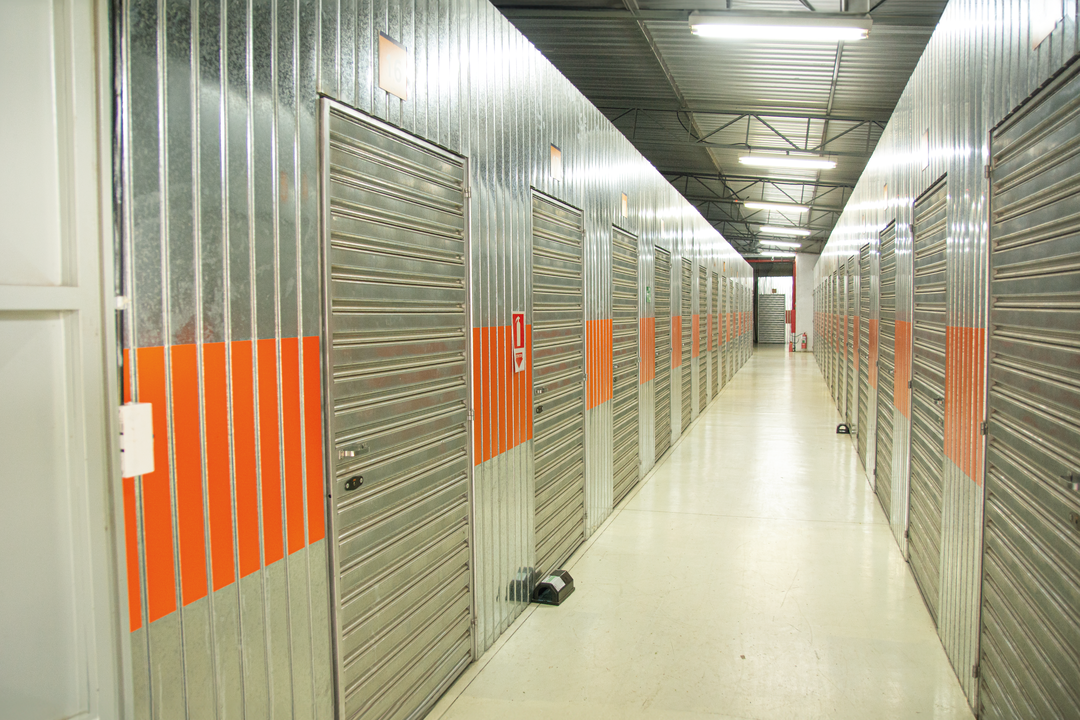 Corredor interno de self storage Mogi das Cruzes, com boxes metálicos individuais alinhados, iluminação adequada e estrutura organizada para armazenamento seguro.