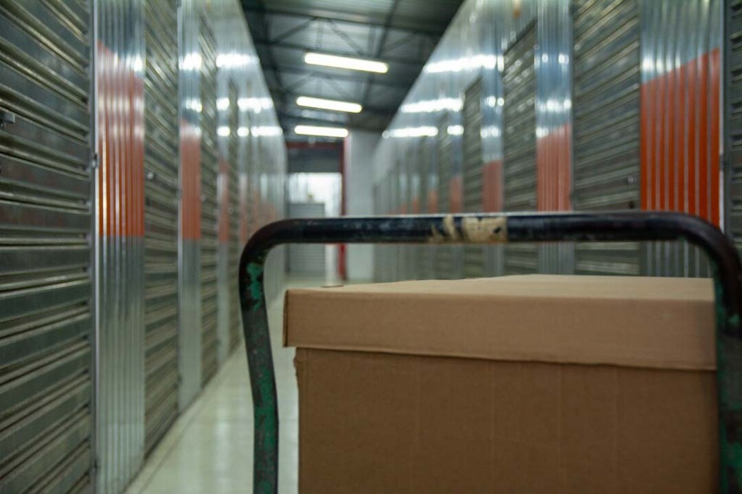 Corredor de self storage com box no nível térreo e carrinho de transporte, ilustrando o acesso facilitado de um box horizontal self storage para movimentação de itens.