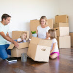 Família organizando caixas em uma nova casa durante mudança, situação comum em que o uso de guarda-móveis em Mogi das Cruzes ajuda a armazenar móveis e objetos temporariamente.